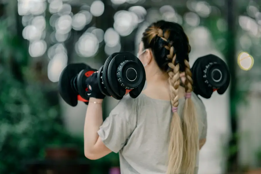 Image of a woman using dial adjustable dumbbells