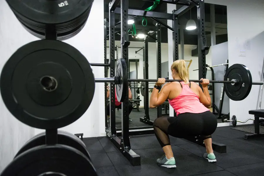 Woman squatting in a barbell cage